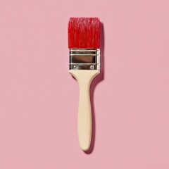 A close-up of a paint brush with a red brush head on a pink background