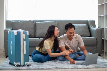 Happy couple planning travel with laptop and packed suitcase.