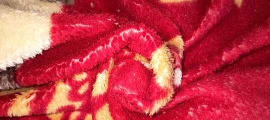 Red and beige fleece fabric with an abstract pattern is crumpled. The fabric texture appears © captanjacksparrow