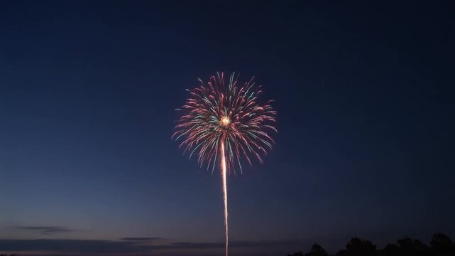Time-lapse style shot of a single firework going off against a rapidly darkening twilight sky