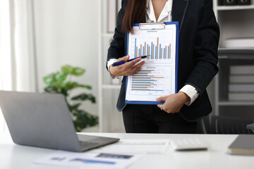 Asian businesswoman showing charts and explaining business strategies using video conference on laptop.