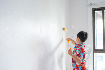 Little school boy enjoy rolling paint interior wall cozy room
