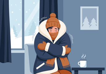 Person bundled in warm clothing feeling cold indoors with a hot drink.