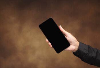 Hand holding smartphone with blank black screen.