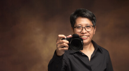 Photographer holding camera forward in studio portrait.