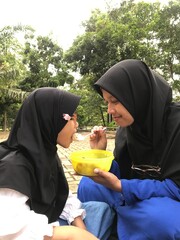 Muslim Mother Gently Feeding Her Daughter in the Open Air