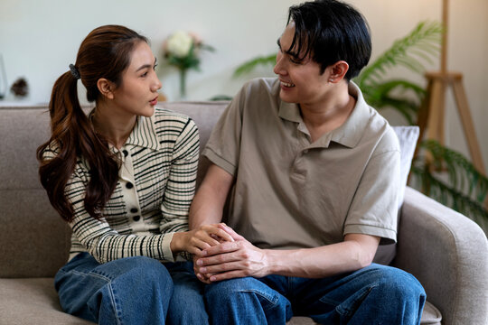 asian adult couple engage deep conversation holding hands offering emotional support cozy home living room setting - Powered by Adobe