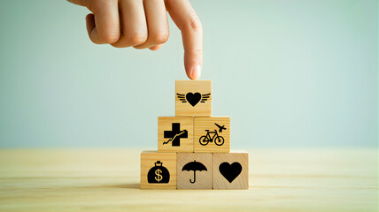 Hand stacking wooden cubes with various life icons, symbolizing comprehensive protection, personal well-being, and future planning for health, finance, and activities