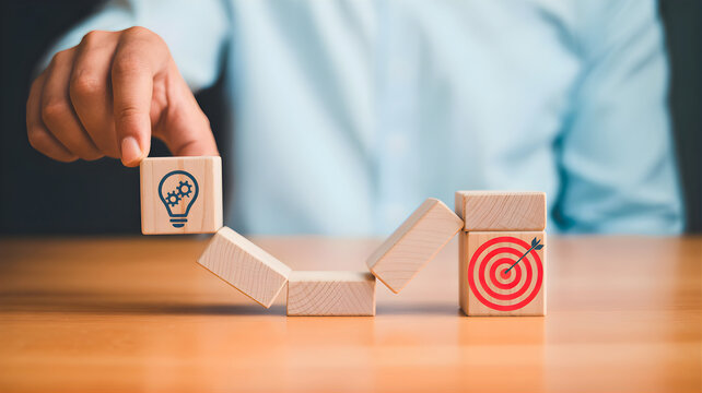 Conceptual image illustrating strategic business development from innovative ideas to successful goal achievement, showing a hand guiding a lightbulb block towards a target on a wooden path