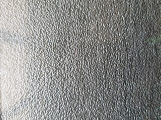 Close-up view of a textured, patterned privacy glass surface diffusing exterior light.