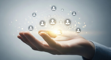 Human hand holding a glowing digital network of connected people icons over neutral gray. It represents global communication, technology, and business connections.