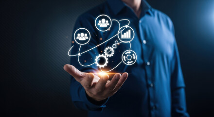 A man in a blue shirt holds a glowing holographic projection illustrating a modern business model with connected icons on a dark, digital technology-focused background.