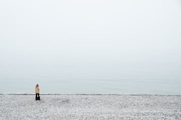 A solitary figure stands gracefully on a misty beach, profoundly embodying tranquility and deep introspection