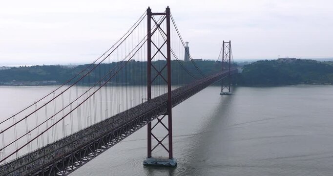 Beautiful aerial drone shot of thousands of long distance half marathon and 10k runners crossing the 25th April bridge in Lisbon, Portugal during a road race. Sports, health, wellbeing and fitness
