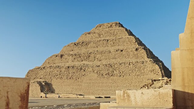 the Step Pyramid of Djoser in the Saqqara necropolis, Egypt, bathed in the warm, golden light of the setting sun.