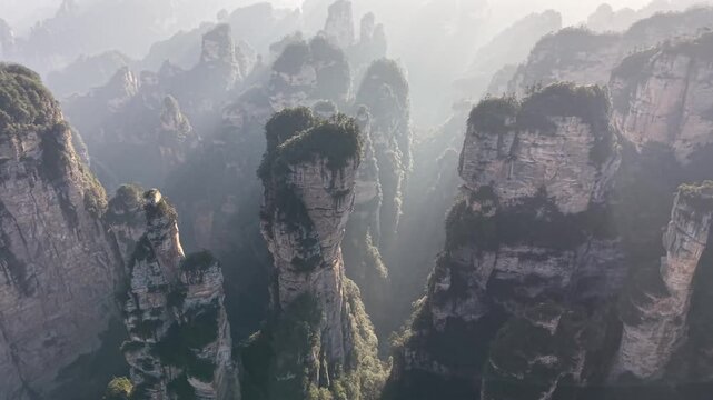 Drone captures powerful godrays at sunrise illuminating floating pillars and deep valleys, Zhangjiajie Avatar mountains, China