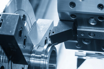 The CNC lathe machine forming cutting the metal tube parts in the light blue scene. © Pixel_B