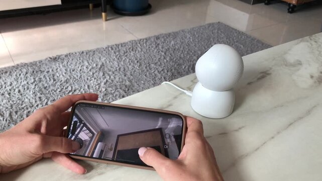 Person using mobile app for remote control of security camera in modern living room. Smart home security system concept