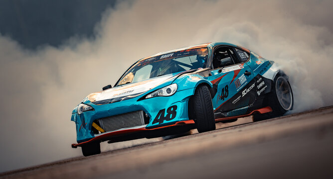 Latvia, Riga 03-05.10.2025. FIA Drifting cup Dynamic blue drift car performing a smoky burnout on an asphalt track with cloudy sky background