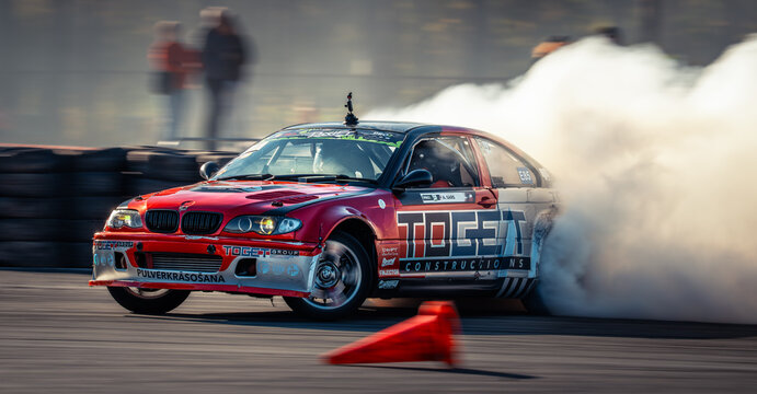 Latvia, Riga 03-05.10.2025. FIA Drifting cup Red drift car performing a smoky burnout on an asphalt track with spectators in the background