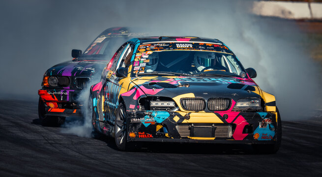Latvia, Riga 03-05.10.2025. FIA Drifting cup Two colorful drift cars racing on a track with smoke trailing behind them