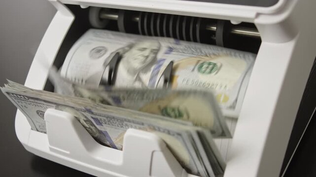 Cash counting process with hundred dollar notes. Banking operation and finance with money movement. Counting machine working in bank. Banking system processing currency. Counting money in motion.