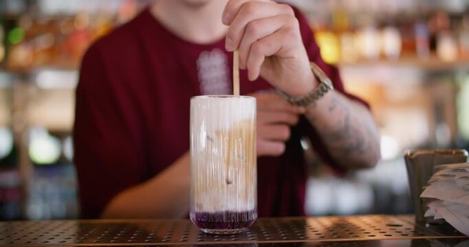 Garnishing drink. Bartender service. Worker painting pattern on whipped cream top cocktail. Preparing sweet flavored aroma cold beverage.
