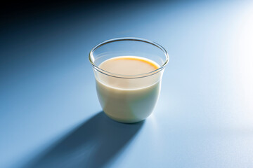 青背景に置かれたミルク系飲料とグラスのシンプル構図