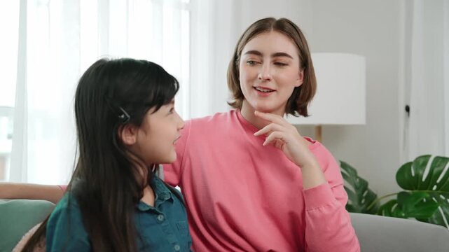 Caucasian mother telling her story to cute daughter while girl listening the fairytail. Happy mom tell and exchange experience to young student while happy attractive child sitting at sofa. Pedagogy.