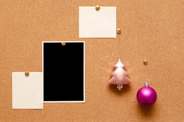 Empty photos and Christmas tree toys are pinned on a cork board. Copy space