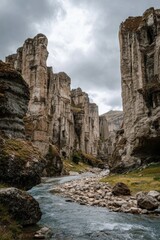 Naklejka premium Dramatic Stone Pillars Tower Above Craggy Riverbed Under Overcast Skies