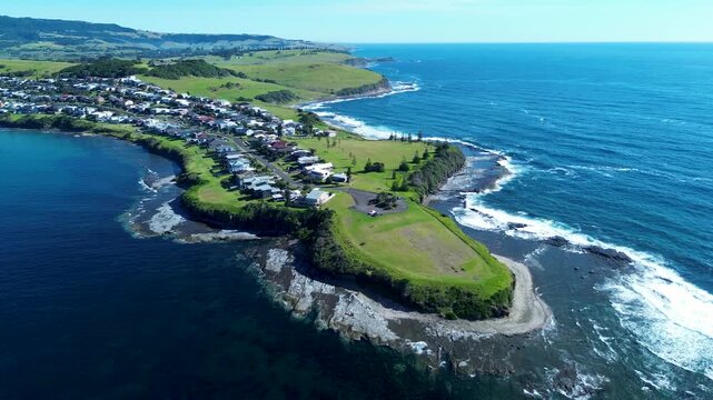 Drone aerial landscape of Gerroa rural town coastline headland with ocean waves crashing on rocky reef beside housing on street suburb in Illawarra South Coast Kiama Australia tourism travel outdoors