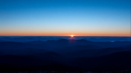 A vibrant sunrise emerges, casting light over layered mountain ranges against a gradient sky
