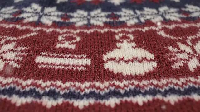 Close up of a festive knitted Christmas sweater pattern with ornaments and snowflakes.