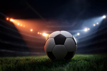 Fototapeta premium Soccer ball on stadium grass under dramatic match lighting