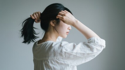 Fototapeta premium 髪を後ろでまとめてポニーテールに結ぶ若い女性