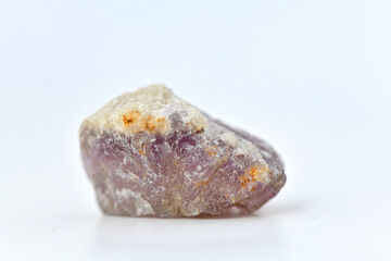 A raw, rough specimen of purple Fluorite, also known as fluorspar, showcasing its characteristic glassy luster and crystal form on a clean white background.