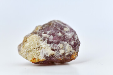 A raw, rough specimen of purple Fluorite, also known as fluorspar, showcasing its characteristic glassy luster and crystal form on a clean white background.