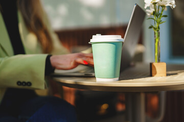 Working on a laptop outdoors with coffee and flowers on the table