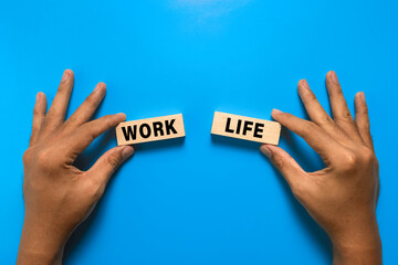 male hand hold work and life words on wooden blocks. isolated on blue background