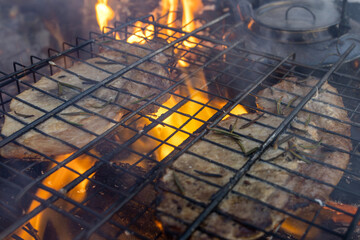 Grilling steaks over a campfire in the forest.
