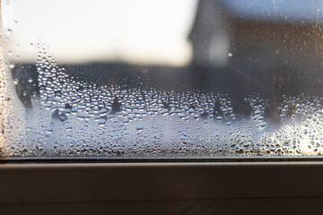 Water droplets accumulate on the interior of a glass window, revealing high humidity. This suggests inadequate air circulation which can lead to mold and mildew growth indoors.