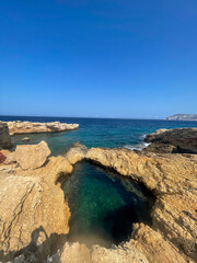 Rocky coastal pool beside turquoise Aegean sea waters, Cyclades islands Greece. Calm sea, summer vacation destination
