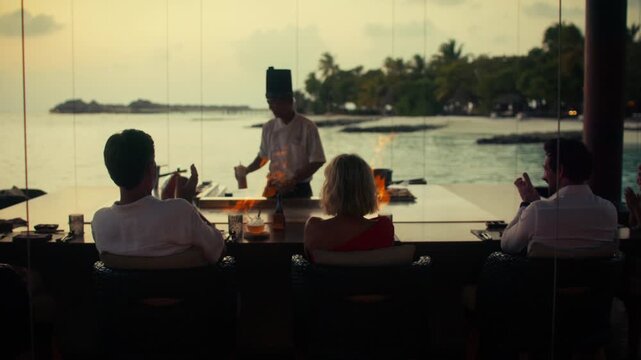 Chef performs an exciting teppanyaki fire show for delighted guests at a luxury resort restaurant