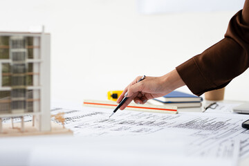 Close up hand of Architect or engineer professional holding pen working on blueprint , structural floor plans, triangular scale , Shop drawing , calculator, laptop and engineering tools.