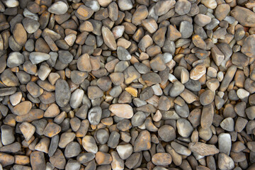 Natural river stones in various shades of gray, brown, and beige are scattered across the surface, creating a textured and visually appealing background for design purposes