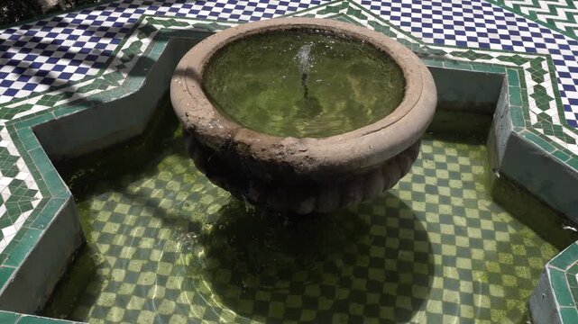 A simple water fountain in the middle is surrounded by a really cool Moroccan tile pattern on the floor.