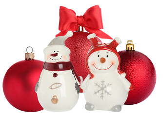 a charming studio photograph of two festive snowman figurines and classic red christmas baubles, isolated on black.