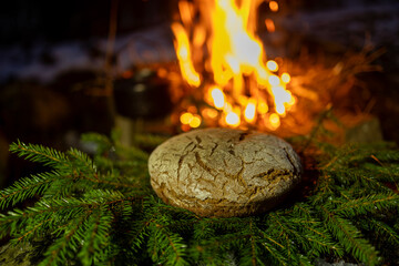 Homemade round bread against the backdrop of a bonfire