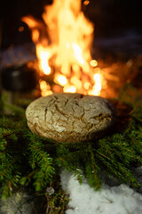 Homemade round bread against the backdrop of a bonfire